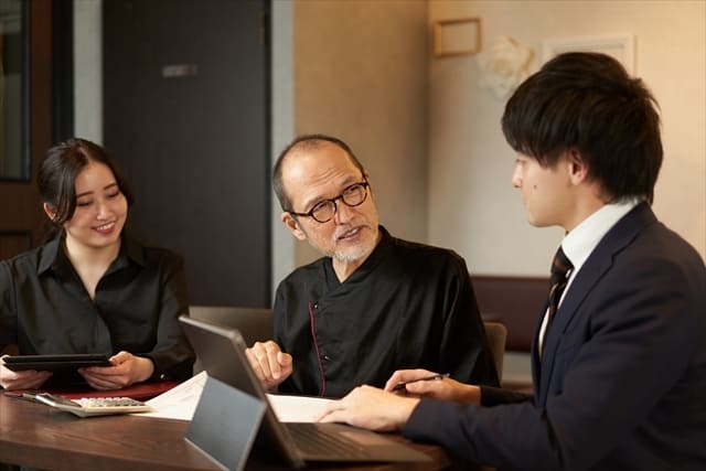 中年男性の話を聞く二人の若者