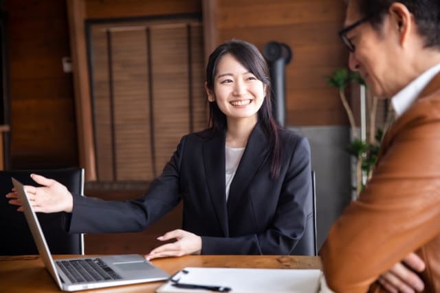 PCを男性に見せる笑顔の女性